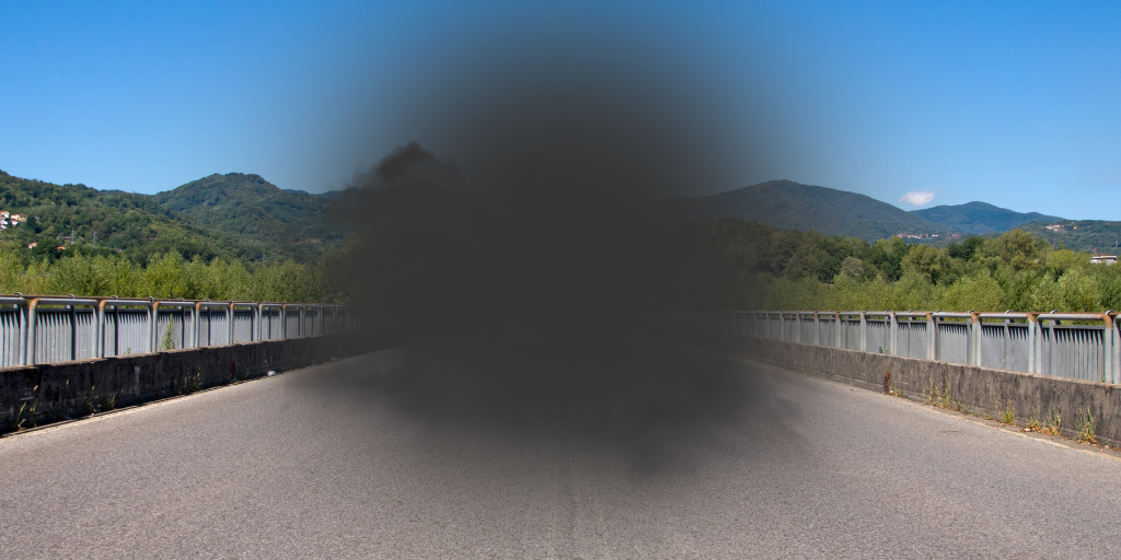 Road with mountains in background and black blur in center, depicting macular degeneration, loss of sight in center