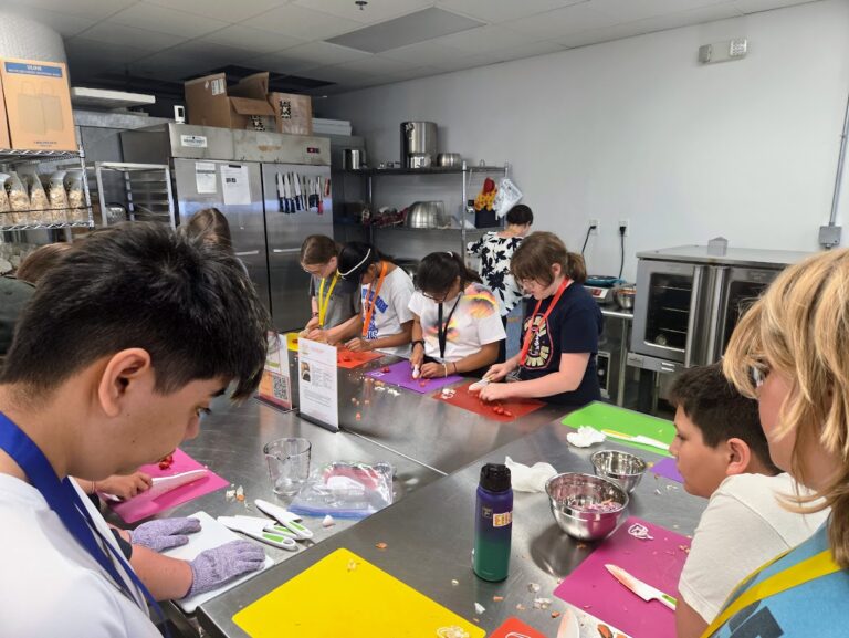 A Trip to Cosley Zoo with Grandma Martyl's Low Vision Day Camp 39 young people around a stainless tell table prepping food.