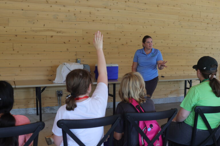 A Trip to Cosley Zoo with Grandma Martyl's Low Vision Day Camp 9 young person raises hand during presentation.