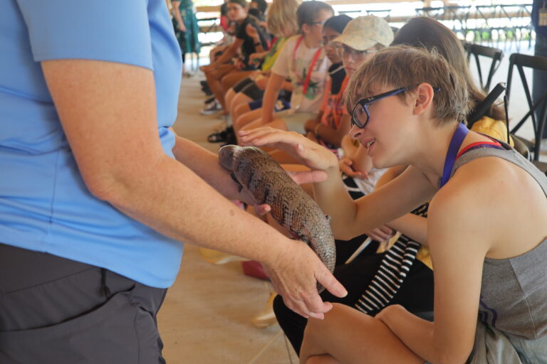 A Trip to Cosley Zoo with Grandma Martyl's Low Vision Day Camp 11 a young person pets a skink that is being held.